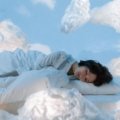 A relaxed traveler sleeping soundly on a long flight with a comfortable U-shaped memory foam travel pillow providing excellent neck support, preventing stiffness and promoting well-being for their journey.