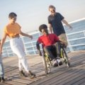 A person smiling in a lightweight, portable travel wheelchair while exploring a beautiful, accessible destination, symbolizing freedom and adventure.