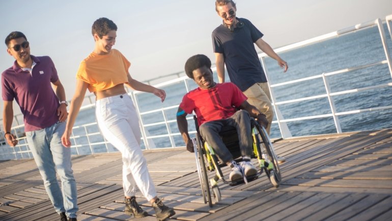 A person smiling in a lightweight, portable travel wheelchair while exploring a beautiful, accessible destination, symbolizing freedom and adventure.