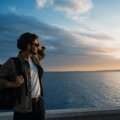 A young traveler with a backpack looks out over a scenic mountain vista, an example of an affordable and authentic experience made possible by budget travel strategies.