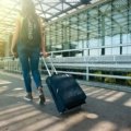 A durable golf travel case with wheels, either a hard or soft shell, being effortlessly transported through an airport or hotel lobby, signifying secure protection for valuable golf clubs on a trip.
