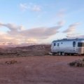 White Casita travel trailer (fiberglass RV) parked at a scenic lakeside campsite at sunset, symbolizing lightweight adventure and easy camping.