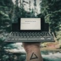 A digital nomad typing on a compact travel keyboard with a tablet, highlighting portable productivity and remote work flexibility in a travel setting.