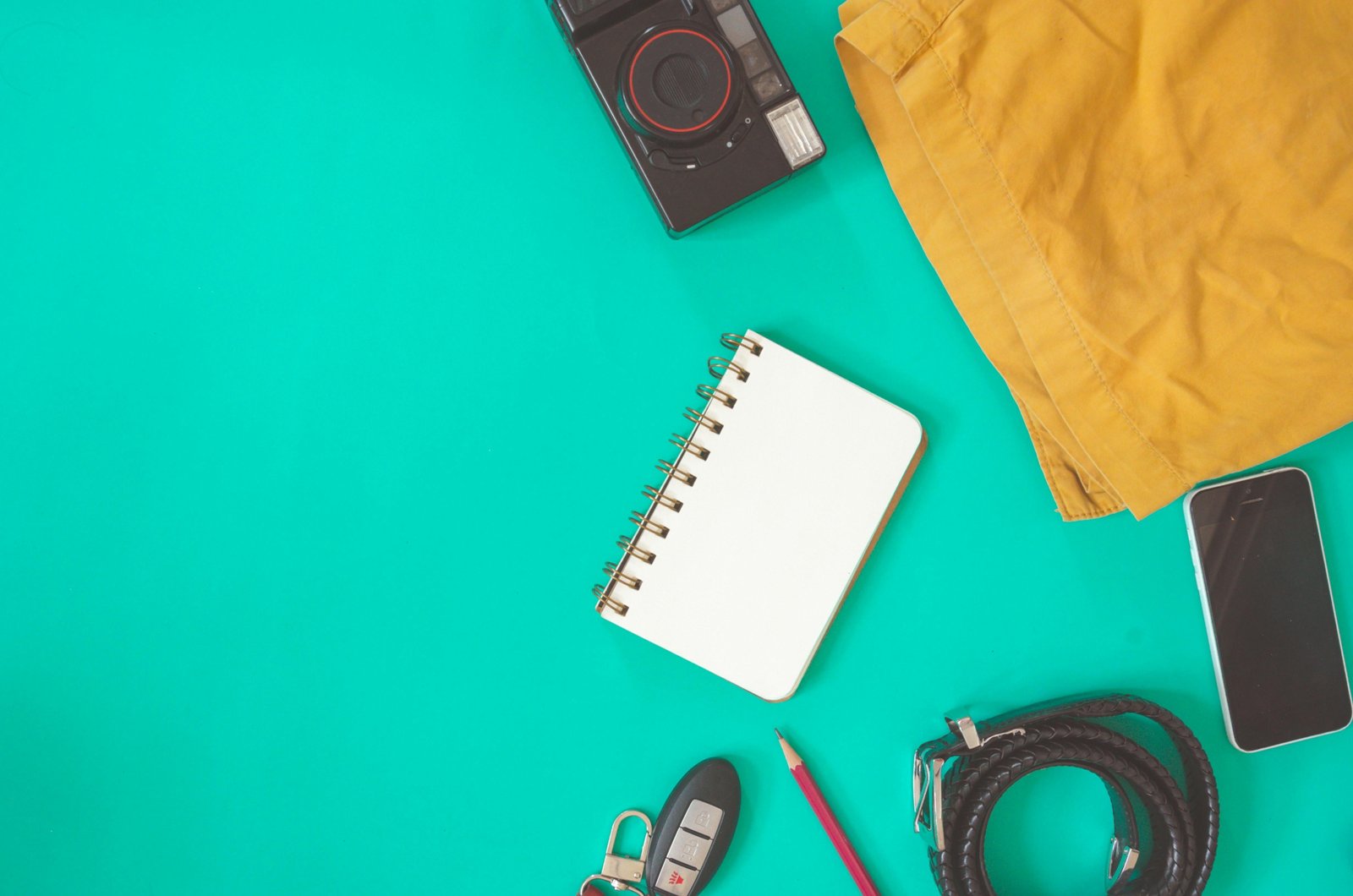 Assortment of travel spray bottles, including a sleek perfume atomizer and a colorful silicone bottle, packed efficiently with other carry-on travel essentials for a light and organized trip.