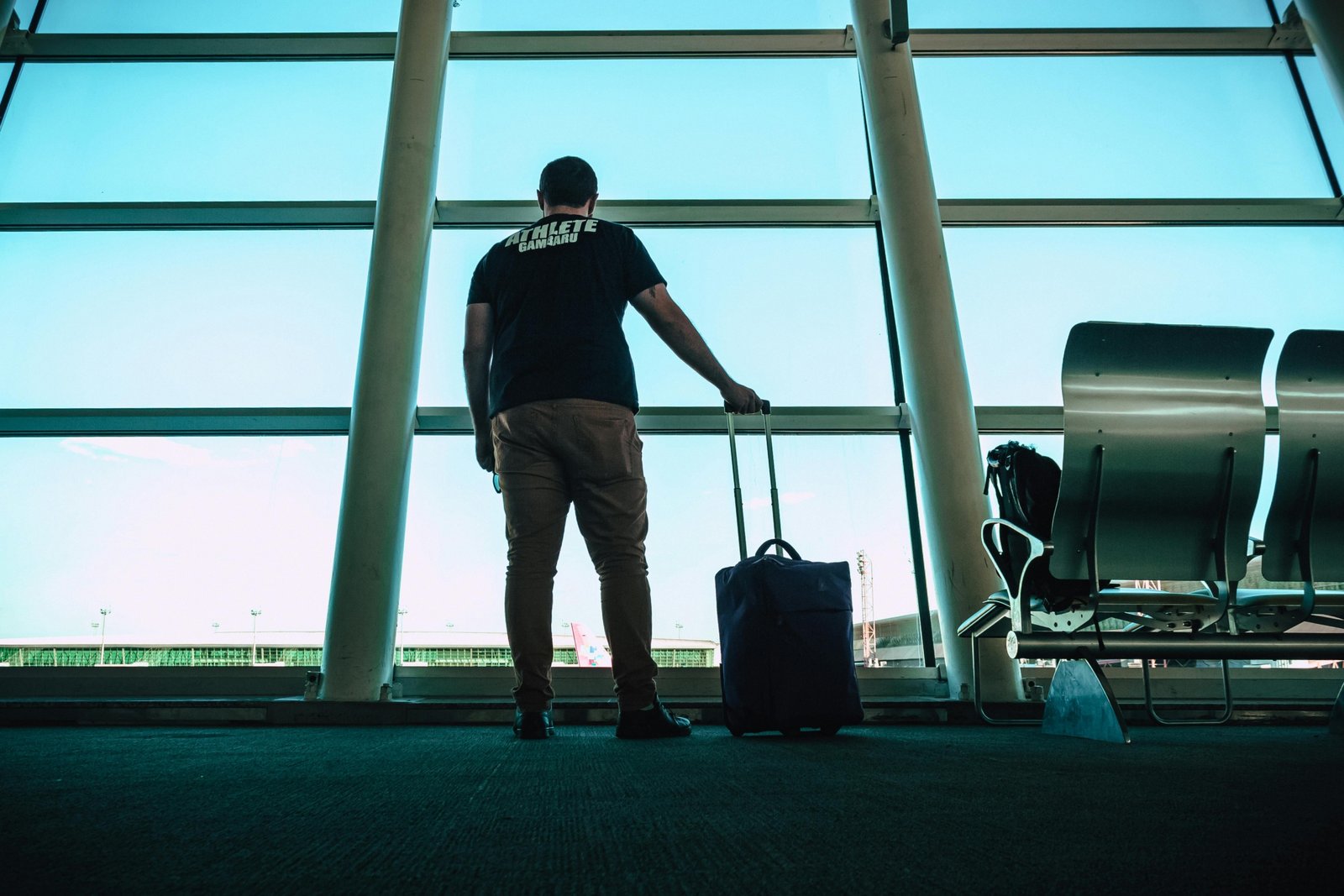 Sleek dark OGIO travel bag with spinner wheels rolling through a bright, modern airport terminal, highlighting durability and functional style for a confident traveler.