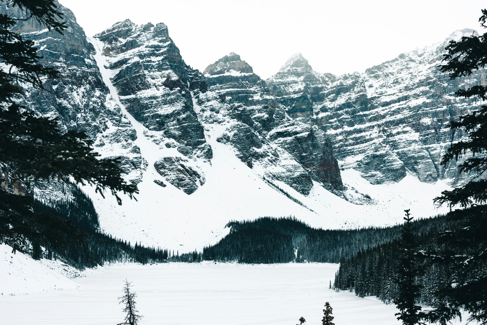 A stunning Canadian winter wonderland scene with pristine snow covering majestic mountains and evergreen forests under a bright, crisp sky, symbolizing the magic and adventure of Canadian winter travel. This image is ideal for articles on essential Canadian winter travel advice, packing tips, and winter activities.