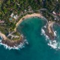 Stunning panoramic view of Sri Lanka featuring sun-kissed beaches, verdant tea plantations, and an ancient temple, symbolizing the island's ideal travel times and diverse regional attractions.