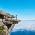 An adventurer stands with a backpack, gazing across a vast, breathtaking mountain range, inspiring exploration for overseas adventure travel in 2025 to destinations like Patagonia, Nepal, or the Azores.