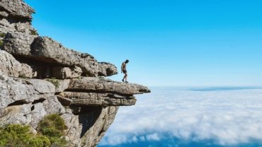 An adventurer stands with a backpack, gazing across a vast, breathtaking mountain range, inspiring exploration for overseas adventure travel in 2025 to destinations like Patagonia, Nepal, or the Azores.