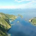 Hidden gems Oceania islands travel guide: Aerial view of a pristine, untouched Pacific island with turquoise lagoon and lush greenery, symbolizing secluded adventure and authentic discovery.