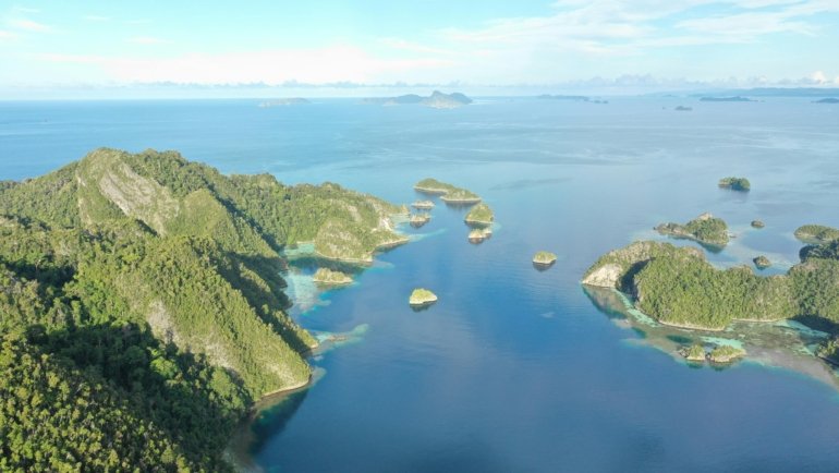 Hidden gems Oceania islands travel guide: Aerial view of a pristine, untouched Pacific island with turquoise lagoon and lush greenery, symbolizing secluded adventure and authentic discovery.