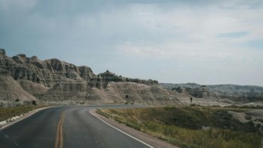 Scenic road winding through dramatic South Dakota landscapes, such as Badlands National Park or the Black Hills, ideal for an adventurous American road trip.