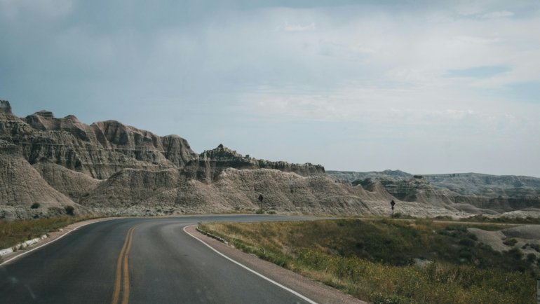 Scenic road winding through dramatic South Dakota landscapes, such as Badlands National Park or the Black Hills, ideal for an adventurous American road trip.