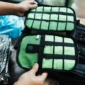 Person packing a suitcase efficiently with various compression packing cubes, demonstrating space-saving and organized travel luggage.