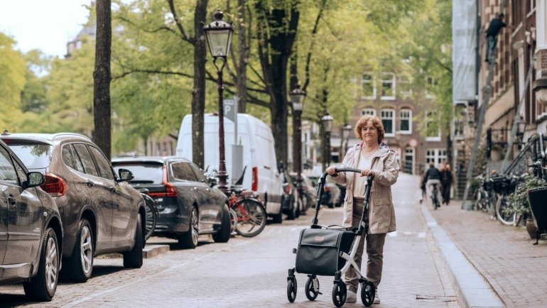 Happy senior traveler taking a rest on a lightweight folding travel walker with a seat in a scenic outdoor setting, symbolizing independence and the joy of exploring new places.