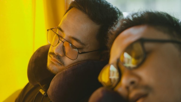 Person sleeping comfortably on airplane with ergonomic memory foam travel neck pillow, preventing neck pain and providing superior support.