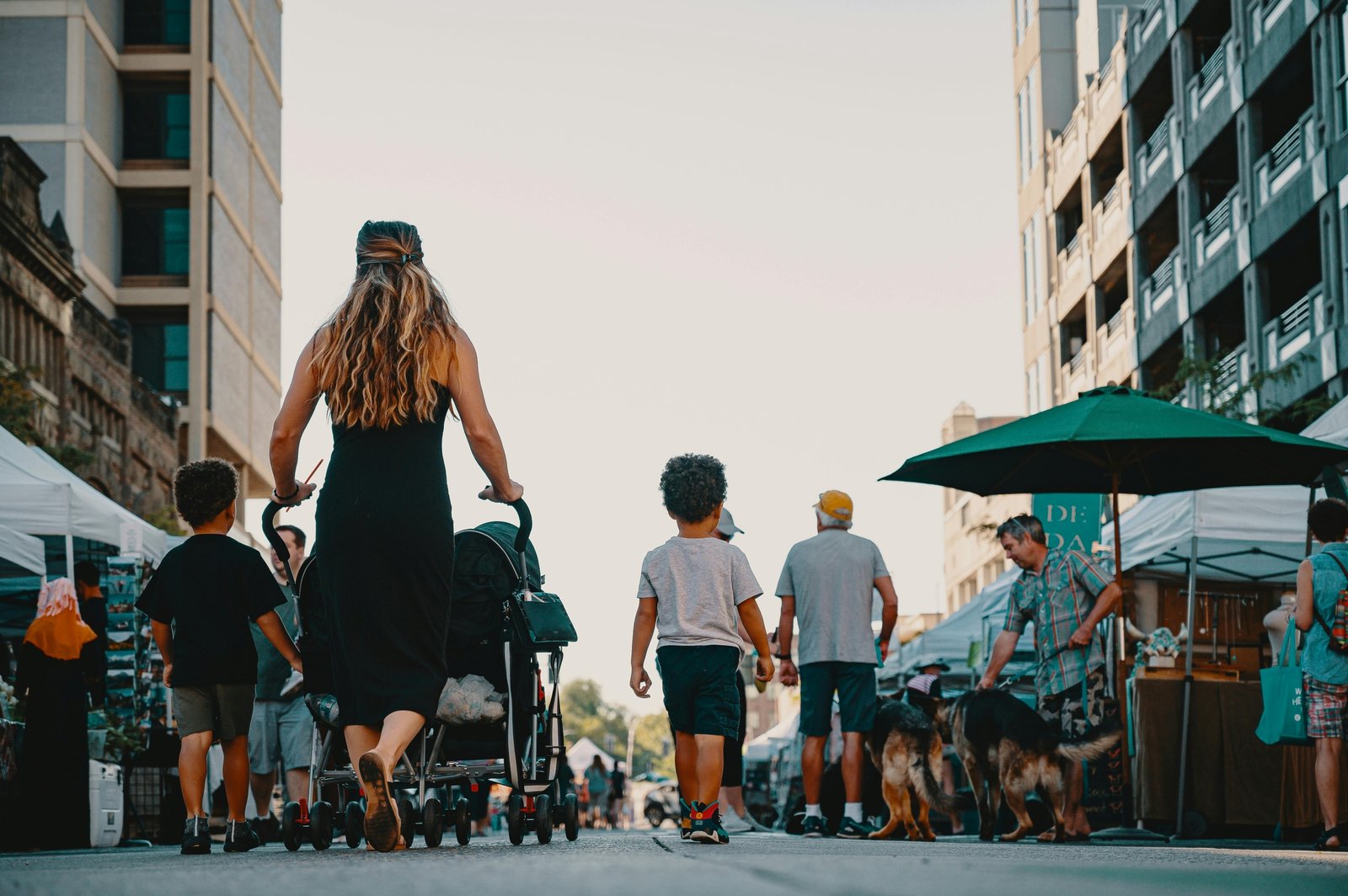A parent confidently pushes a modern Zoe Traveler stroller with a happy baby through a busy airport terminal, showcasing its lightweight and compact design for convenient family travel.