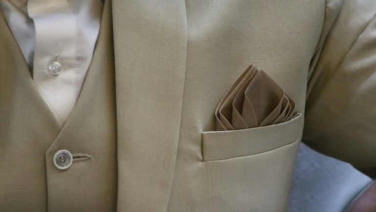 Hands demonstrating the inside-out fold method for packing a suit jacket, ensuring a wrinkle-free arrival for business travel.