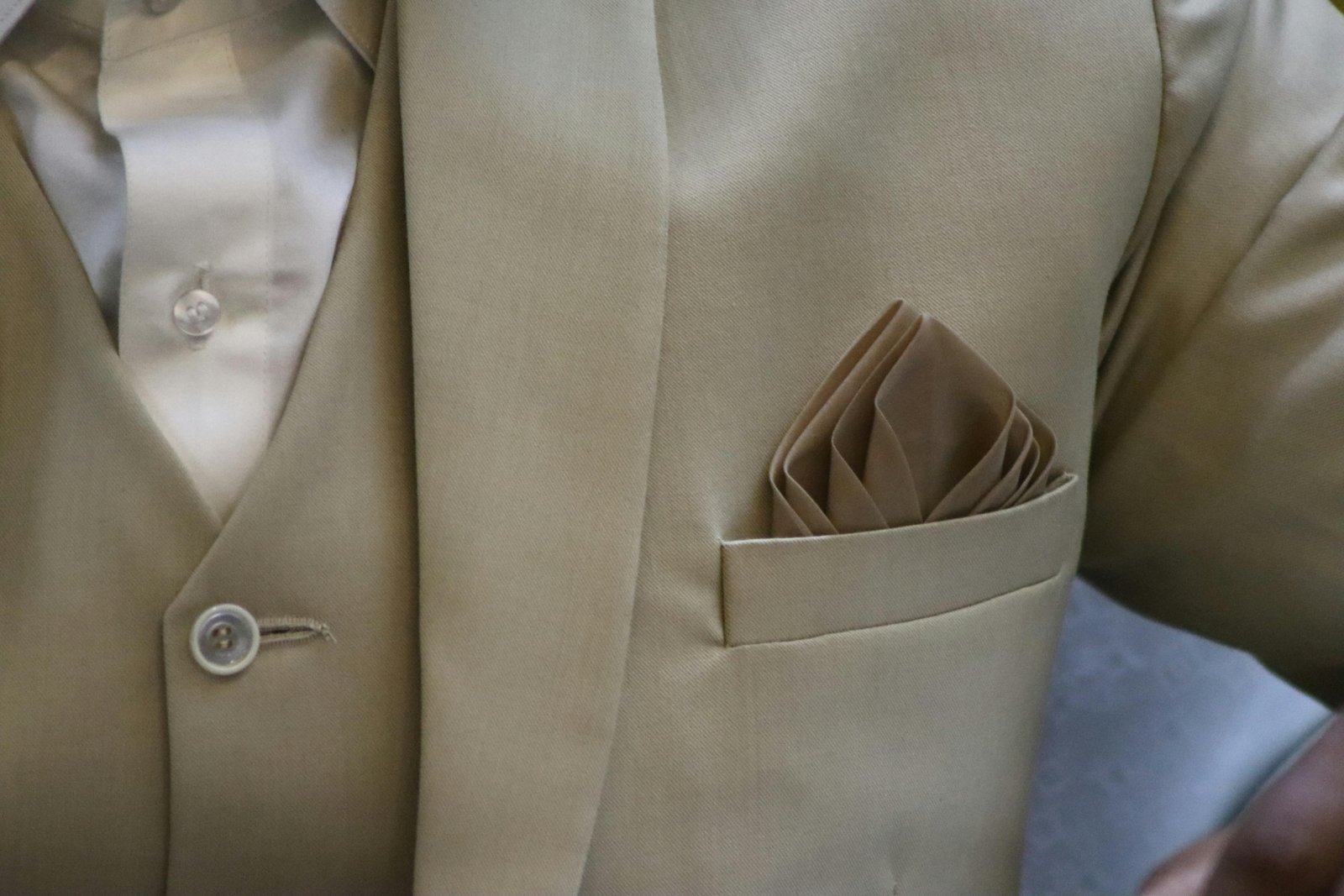 Hands demonstrating the inside-out fold method for packing a suit jacket, ensuring a wrinkle-free arrival for business travel.