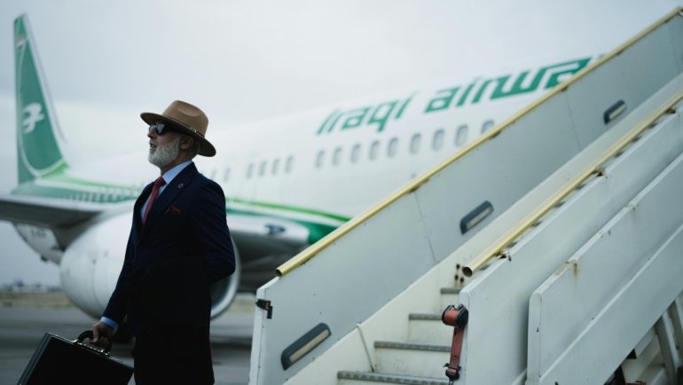 Stylish man confidently walking through an airport wearing a wrinkle-resistant men's travel blazer, showcasing professional yet comfortable business travel attire.