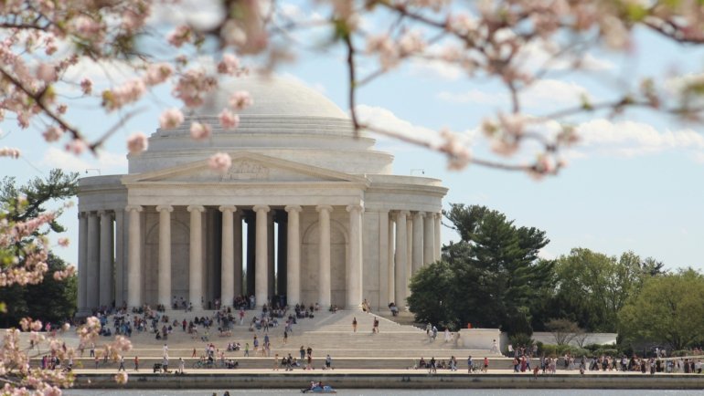 Pink and white cherry blossoms framing the Jefferson Memorial around the Tidal Basin in Washington D.C. during the National Cherry Blossom Festival, illustrating a top March travel destination in the US.