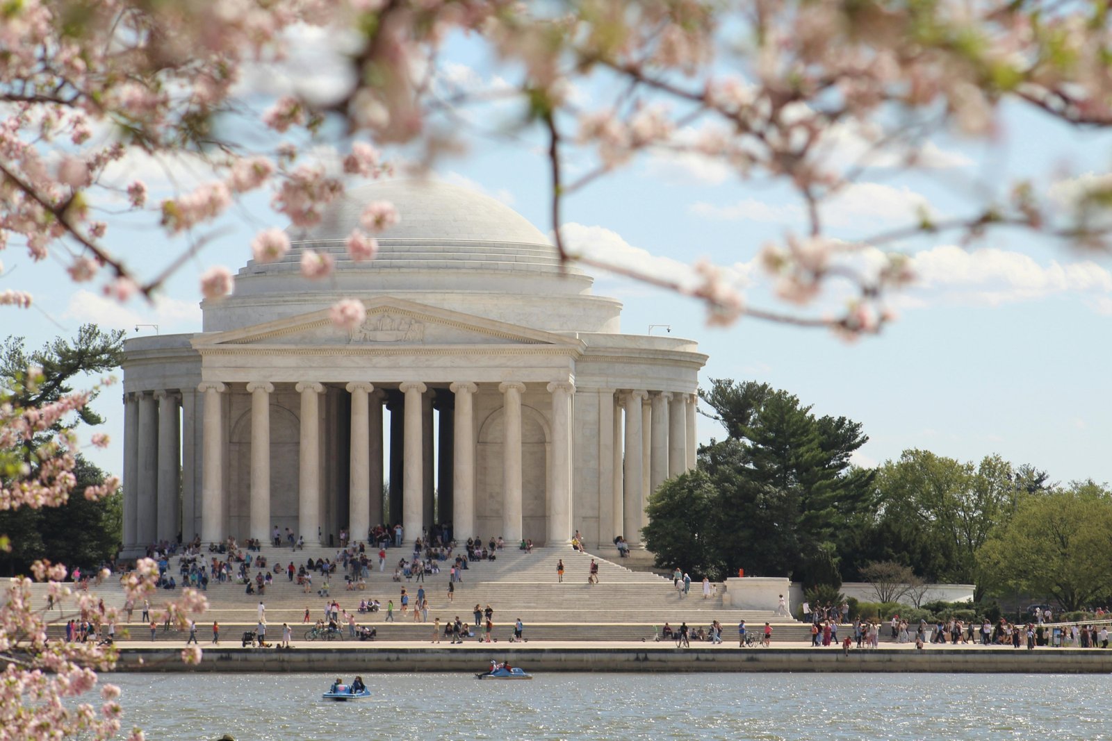 Pink and white cherry blossoms framing the Jefferson Memorial around the Tidal Basin in Washington D.C. during the National Cherry Blossom Festival, illustrating a top March travel destination in the US.