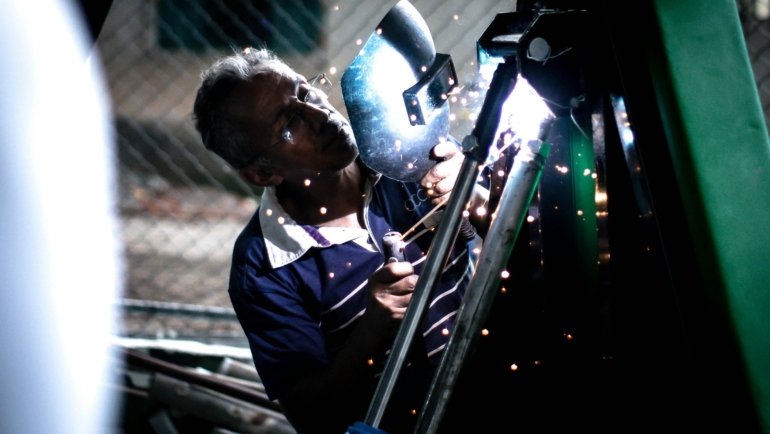 Skilled traveling welder sparks flying on an industrial construction site, highlighting a high-demand, high-paying career in oil and gas or power generation.