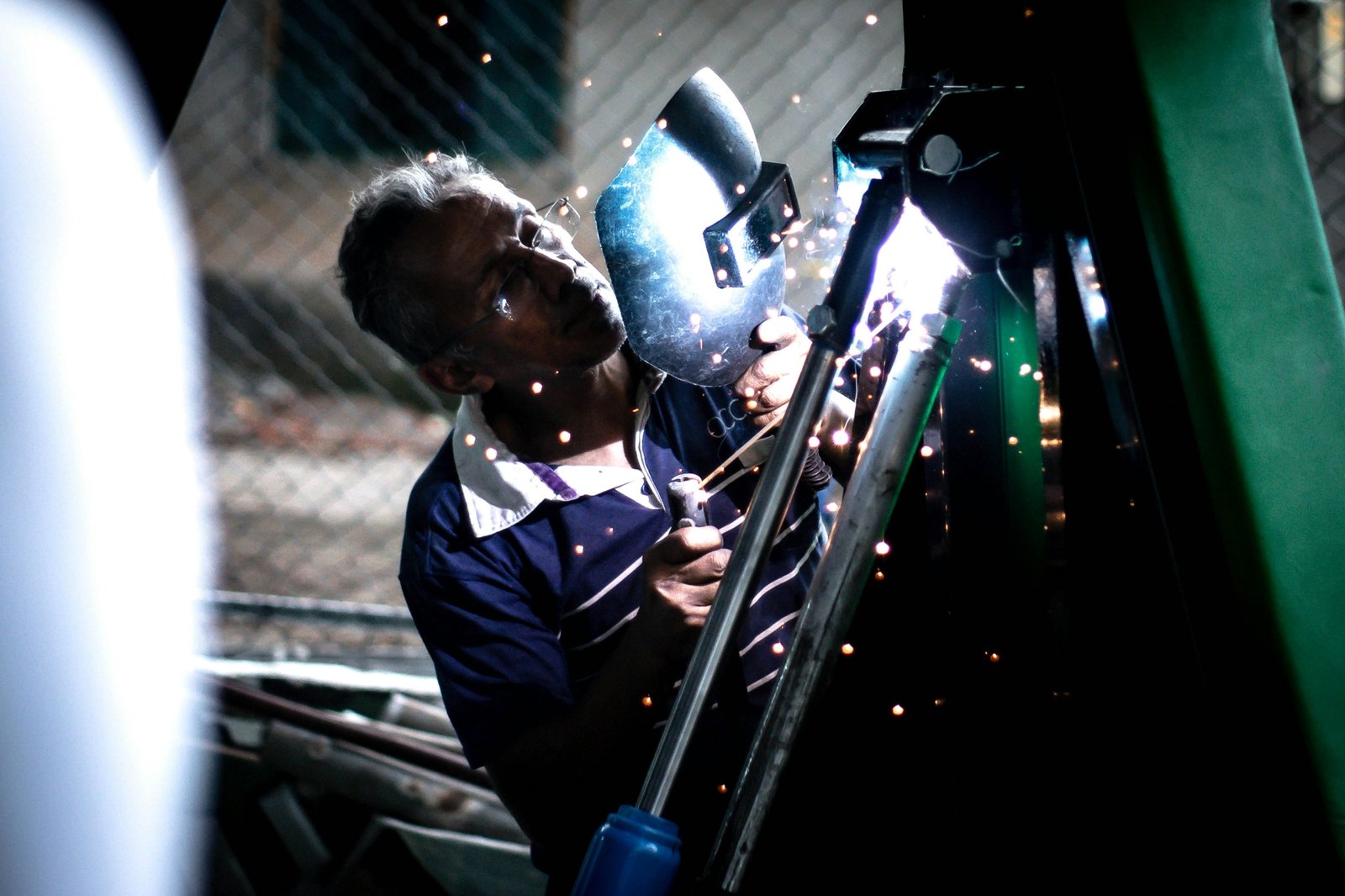 Skilled traveling welder sparks flying on an industrial construction site, highlighting a high-demand, high-paying career in oil and gas or power generation.