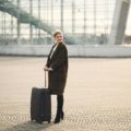 Stylish person with a luxury Gucci-style travel bag in an elegant airport terminal, showcasing high-end travel and iconic design.
