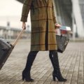 A traveler confidently walking with a sleek, black spinner cabin bag through a bright, modern airport terminal, illustrating the benefits of the best carry-on luggage for smooth journeys.