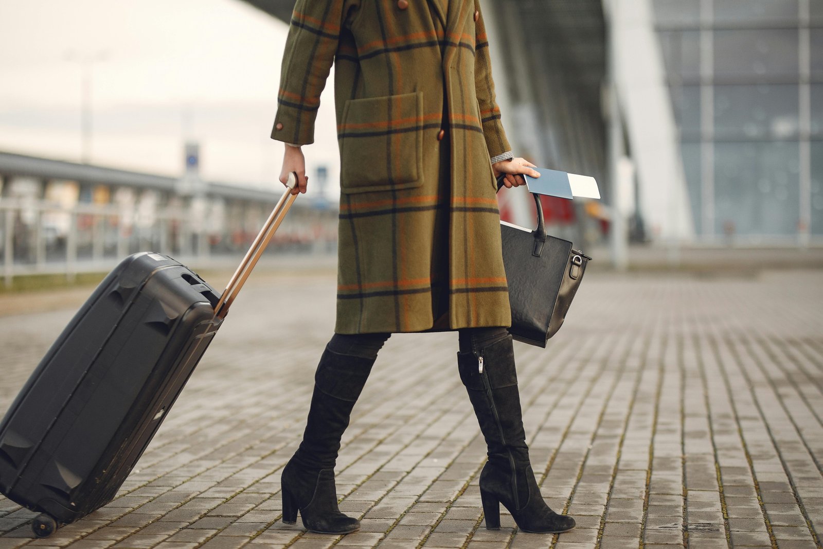 A traveler confidently walking with a sleek, black spinner cabin bag through a bright, modern airport terminal, illustrating the benefits of the best carry-on luggage for smooth journeys.