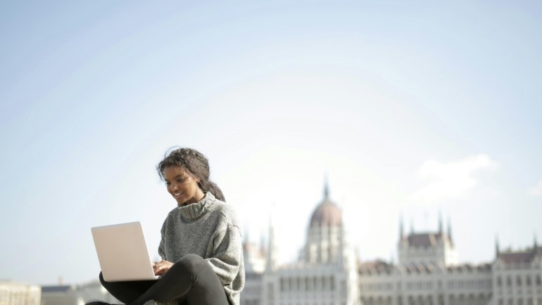 Happy travel nurse working remotely on a laptop, symbolizing flexible part-time telehealth jobs and a balanced career.