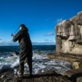 Adventurous angler with a portable travel fishing rod and backpack enjoying fishing in a scenic natural landscape, highlighting convenience for travel.