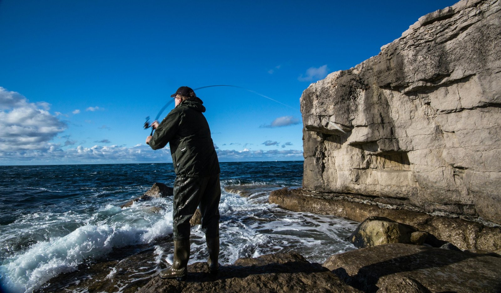 Adventurous angler with a portable travel fishing rod and backpack enjoying fishing in a scenic natural landscape, highlighting convenience for travel.