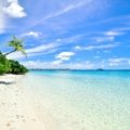 Idyllic tropical travel destination featuring a pristine white-sand beach, clear turquoise waters, and swaying palm trees, perfect for a luxury dream vacation in 2025.