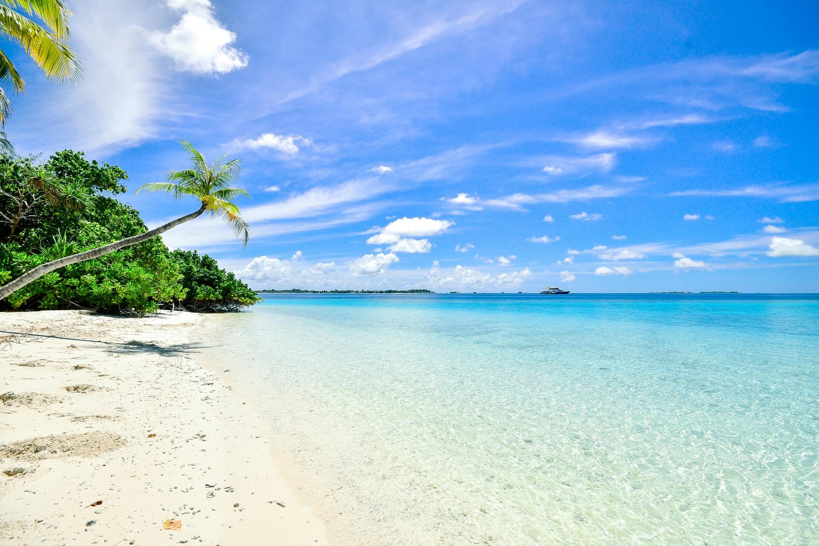 Idyllic tropical travel destination featuring a pristine white-sand beach, clear turquoise waters, and swaying palm trees, perfect for a luxury dream vacation in 2025.