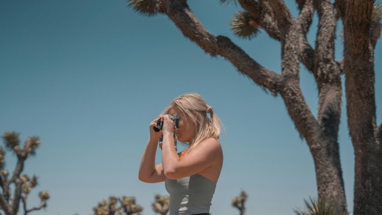 A traveler captures a stunning scenic landscape with a compact travel camera, emphasizing the joy and ease of creating memorable vacation photographs.