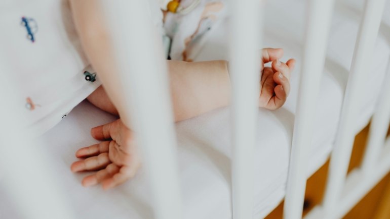 A baby sleeping soundly in a portable travel crib, emphasizing safety and comfort for worry-free family adventures.