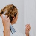 Confident woman using a travel size hairspray to perfect her hairstyle while traveling, showcasing beauty on the go.