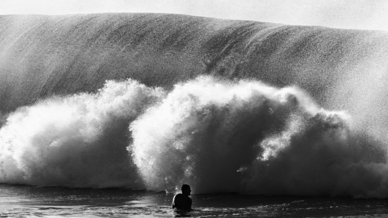 Massive tsunami wave approaching a coastal town, illustrating the dangerous transformation of a fast-moving deep-ocean wave into a towering destructive force near the shore.