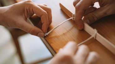 Close-up of an angler's hands expertly tying a detailed fishing fly on a Renzetti Traveler rotary vise, showcasing precision, craftsmanship, and the enjoyment of the fly tying process.
