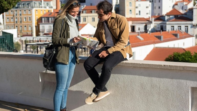 Happy person consulting a map or smartphone to discover local hidden gems, planning a day trip or weekend getaway for an accessible travel adventure near home.