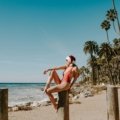 A stunning tropical beach scene with clear turquoise water, white sand, and people enjoying the sun, illustrating an ideal warm place to travel in December for a winter sun vacation.