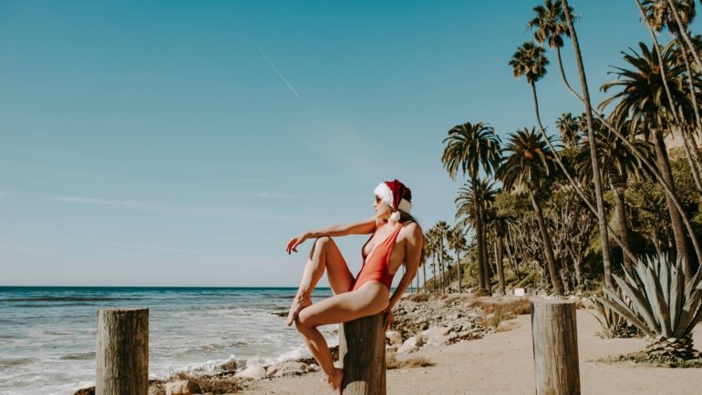 A stunning tropical beach scene with clear turquoise water, white sand, and people enjoying the sun, illustrating an ideal warm place to travel in December for a winter sun vacation.