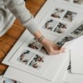 Close-up of hands arranging travel photos, flight tickets, and maps into a personalized DIY travel scrapbook, illustrating the process of creating a memory journal.