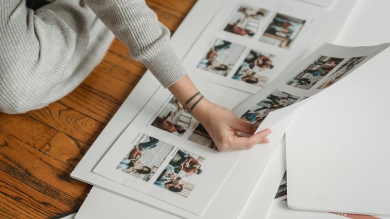 Close-up of hands arranging travel photos, flight tickets, and maps into a personalized DIY travel scrapbook, illustrating the process of creating a memory journal.