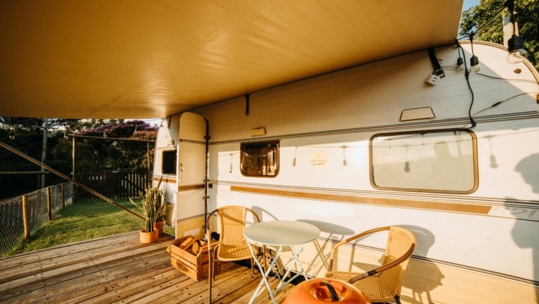 Travel trailer toy hauler with open ramp patio, showing an ATV and people enjoying a scenic outdoor adventure, highlighting versatile RV living.