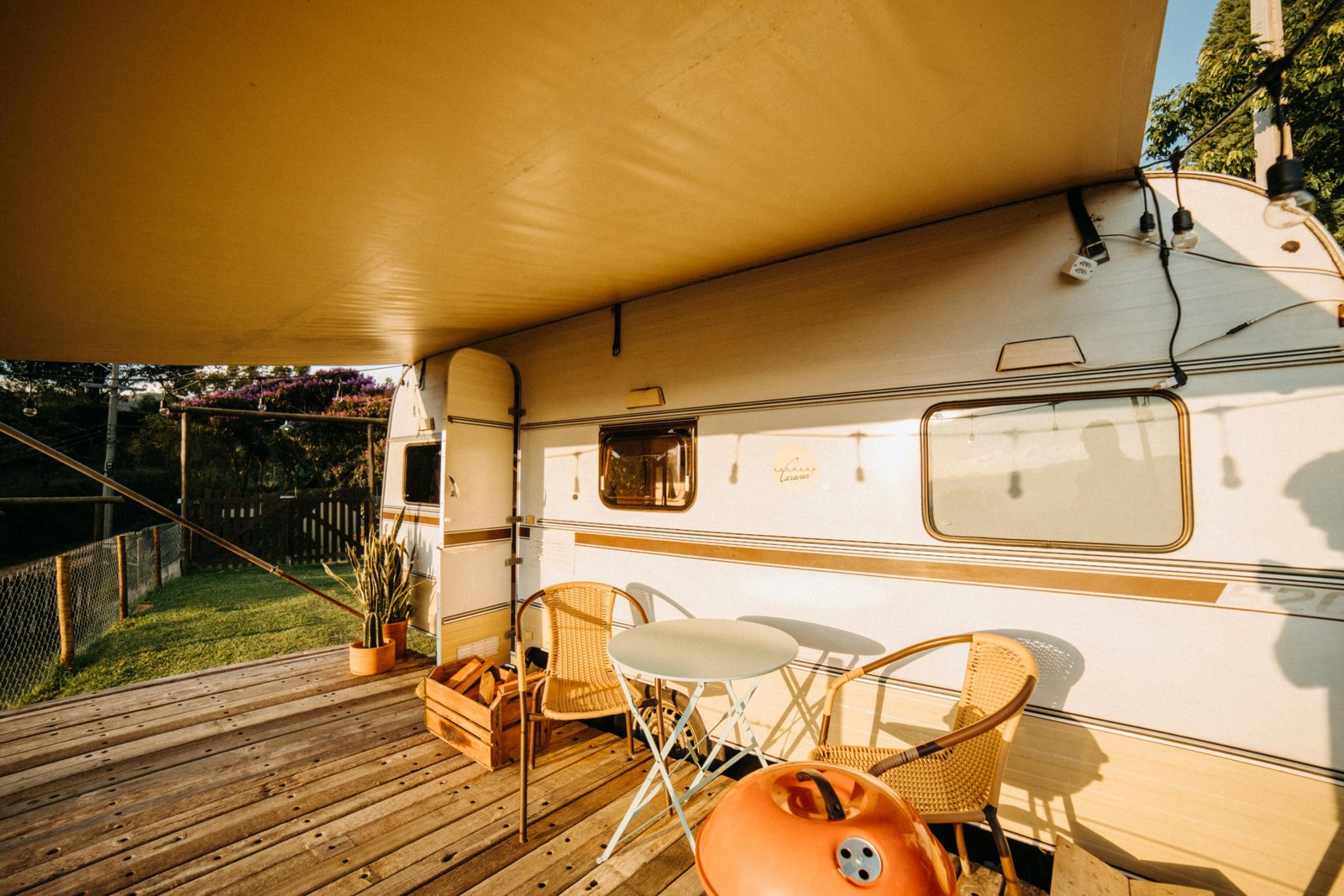 Travel trailer toy hauler with open ramp patio, showing an ATV and people enjoying a scenic outdoor adventure, highlighting versatile RV living.