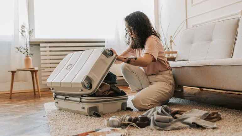 Compact travel hair brush being packed into an open suitcase, symbolizing essential portable beauty tools for smooth, tangle-free hair during travel.