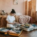 Woman confidently unpacking stylish, wrinkle-free travel clothes from her suitcase in a hotel room, illustrating stress-free packing and an effortless travel wardrobe for women.